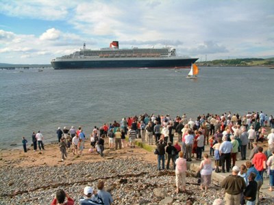 Crowds on the slip watch the QM2 leave the Firth