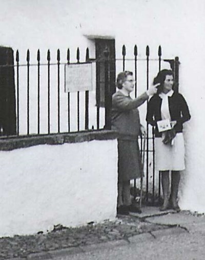 Woman talking outside Hugh Millers Cottage