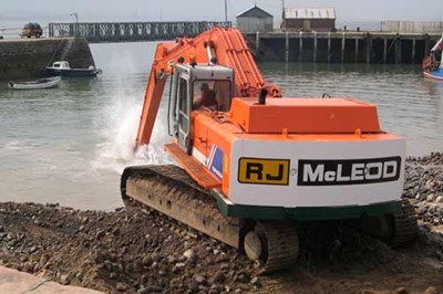 Digger dredging Harbour with pier in background